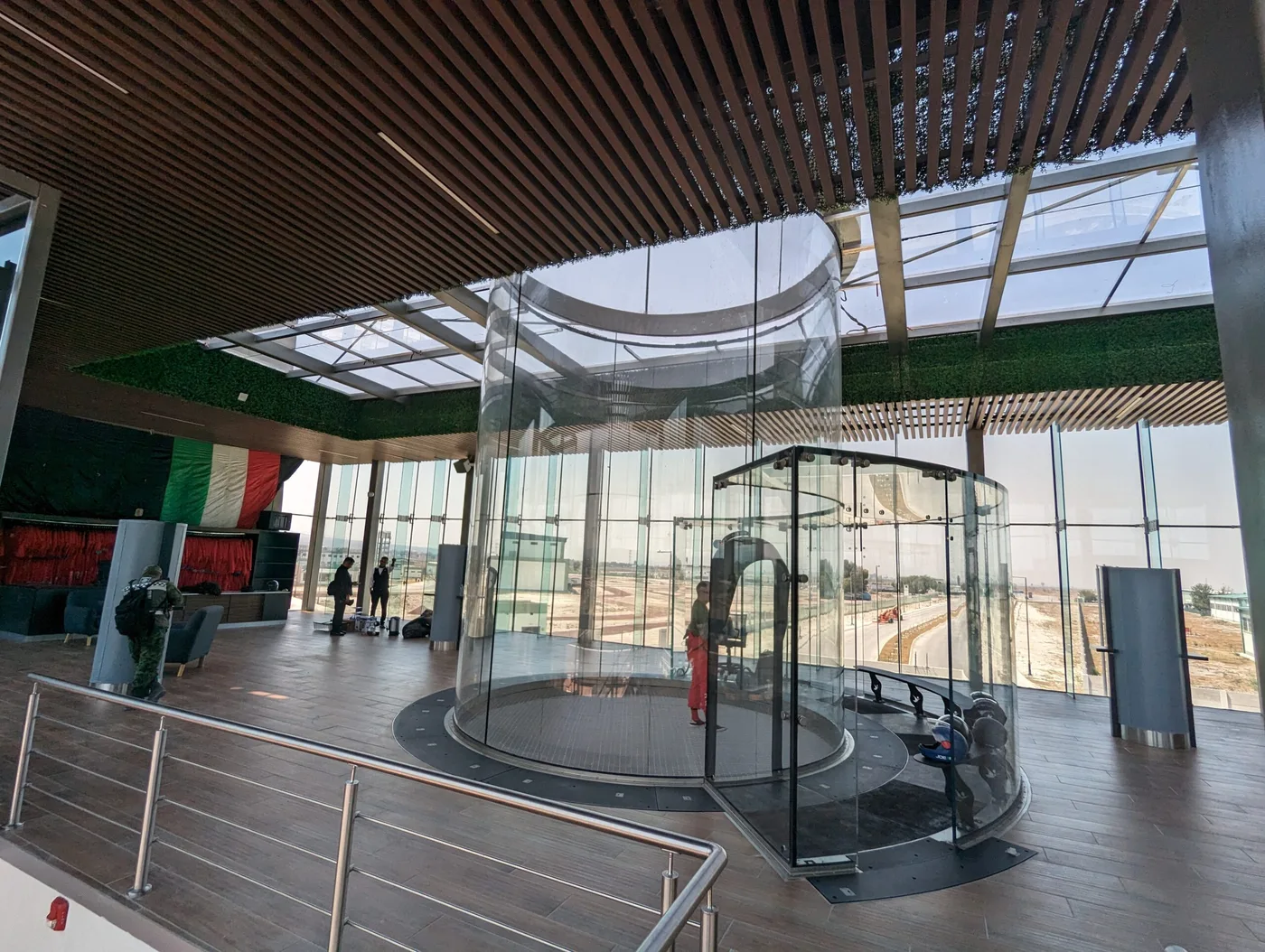 Rooftop glass flight chamber with timber slat ceiling and panoramic glazing — Mexico City